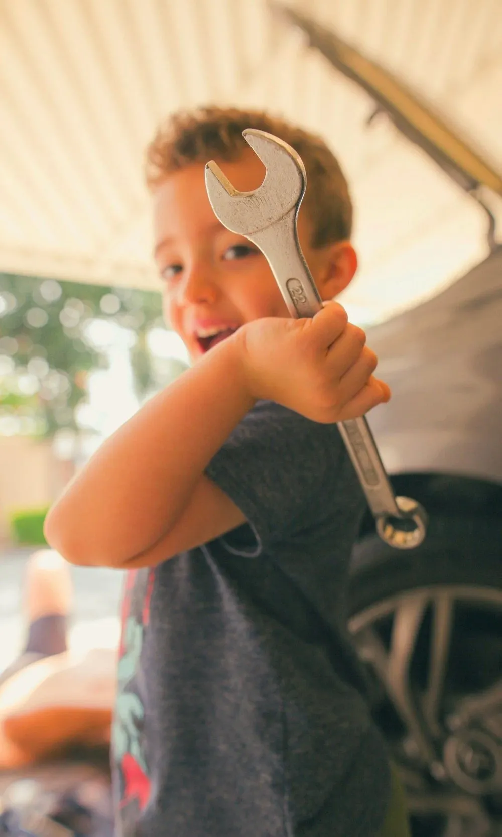 A smiling child holding a wrench